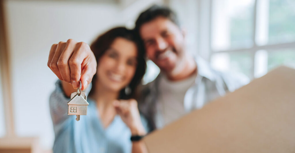 Happy couple holds up keys to their new house.
