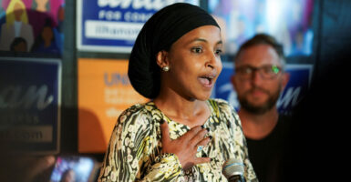 Ilhan Omar speaking at political event, hand on her chest.