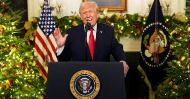 Donald Trump addresses the nation in front of a garland-covered fireplace.