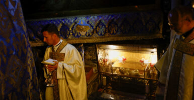 A priest stands near the figure of the baby Jesus at the Grotto in Bethlehem.