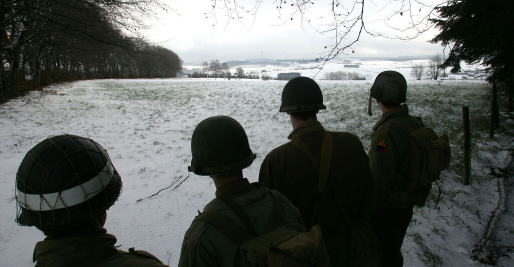 Black-and-white photo of U.S. soldiers overlooking site of Battle of the Bulge.