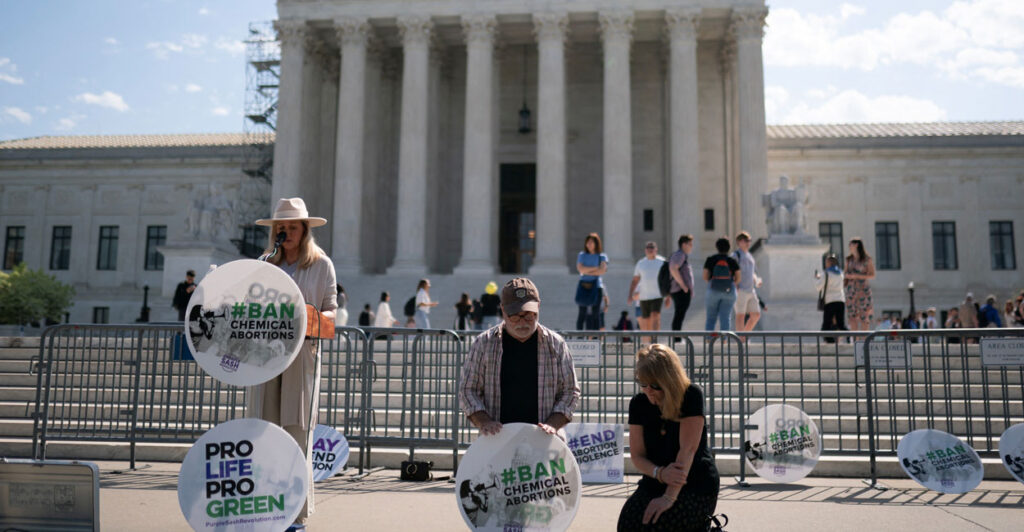 Pro-life activists kneel and stand outside the U.S. Supreme Court.