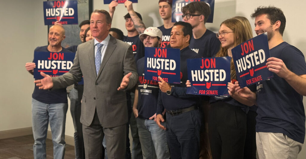 Sen. Jon Husted stands with a crowd of supporters behind him.