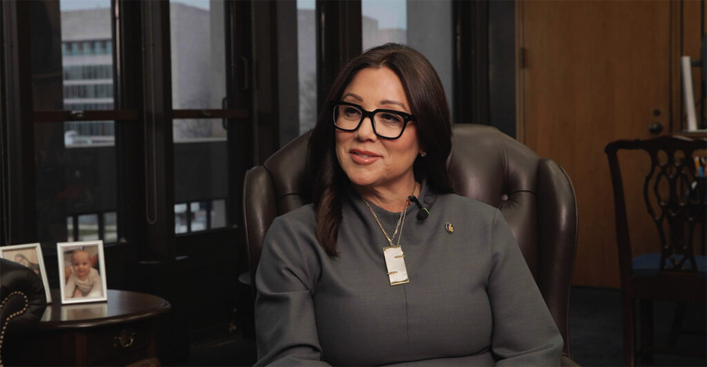 Labor Secretary Lori Chavez-DeRemer in a gray outfit sitting in brown chair during interview.