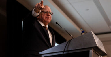 Tim Walz pointing while speaking behind a podium.