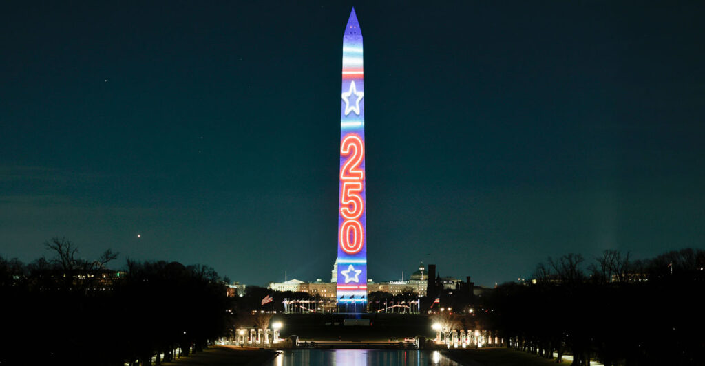 Washington Monument lit up with the projection of "250" in red against a blue background.