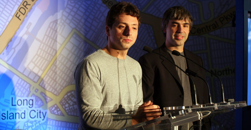 Google founders Google founders Larry Page and Sergey Brin sit at a table in front of a New York road map.