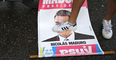 An opponent of Venezuelan President Nicolas Maduro's government steps on an election campaign poster with the image of Maduro during a protest at the Petare neighborhood in Caracas on July 29, 2024, a day after the Venezuelan presidential election. President Nicolas Maduro was declared the winner of Venezuela's presidential election but the opposition and key regional neighbours immediately rejected the official results. (Photo by Raul ARBOLEDA / AFP) (Photo by RAUL ARBOLEDA/AFP via Getty Images)