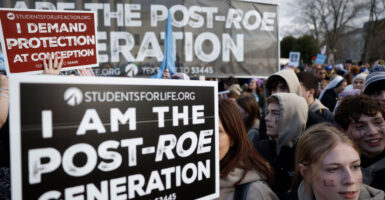 Pro-lifers stand holding their signs, "I AM THE POST-ROE GENERATION."
