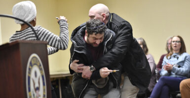 A man is tackled after spraying an unknown substance at US Representative Ilhan Omar (D-MN) (L) during a town hall she was hosting in Minneapolis, Minnesota, on January 27, 2026. US Democratic congresswoman Ilhan Omar was targeted during a speech late on January 27 by a man who sprayed an unidentified liquid at her from a syringe before being tackled by security guards, according to an AFP journalist at the scene. The man was led out of the premises as Omar, a frequent target of attacks by President Donald Trump, continued her speech saying "we will stay resilient in the face of whatever they might throw on us." (Photo by Octavio JONES / AFP via Getty Images)