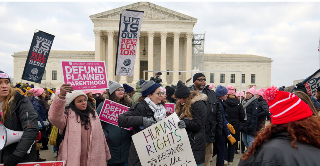 Pro-life activists stand with signs outside of the U.S. Supreme Court.
