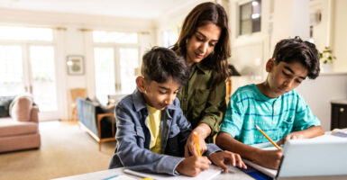 Mother helping tween sons with homework in kitchen