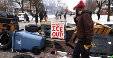 Makeshift barricade set up by anti-ICE protesters blocks Minneapolis street. On barricade is sign reading 