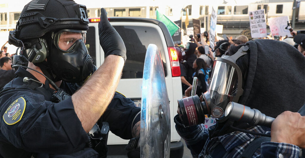A US Department of Homeland Security (DHS) Federal Protective Service (FPS) officer wears a gas mask while blocking a flashlight as protestors clash with Federal agents and police outside the Edward R. Roybal Federal Building and Metropolitan Detention Center during a "National Shutdown" protest against US Immigration and Customs Enforcement in Los Angeles, California on January 30, 2026. Donald Trump's border chief said January 29, 2026 that some federal agents could be withdrawn from Minneapolis, the northern US city that has become the flashpoint for the president's immigration crackdown. The Trump administration, facing a public backlash over the shooting deaths of two Americans by federal agents in Minneapolis, also eased immigration operations in the northeastern state of Maine. (Photo by Patrick T. Fallon / AFP via Getty Images)