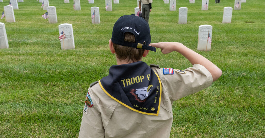 WESTWOOD, CA - MAY 24: Julian Holkenborg of Boy Scout Troop 642 from Woodland Hills salutes after planting a flag at the Los Angeles National Cemetery in Westwood, CA on Saturday, May 24, 2025. He was among the 3,500 boy scouts and girls scouts who planted 90,000 flags ahead of Monday's Memorial Day ceremony. They were instructed to plant one flag per headstone, say the name on the headstone and salute. (Myung J. Chun / Los Angeles Times via Getty Images).