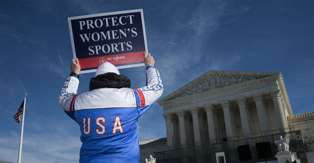 TOPSHOT - A man holds up a sign reading "Protect women's sports" as he demonstrates outside the US Supreme Court as justices hear arguments in challenges to state bans on transgender athletes in women's sports on January 13, 2026, in Washington, DC. The US Supreme Court on January 13 wades into the hot-button issue of transgender athletes in girls' and women's sports. The conservative-dominated court is to hear challenges to state laws in Idaho and West Virginia banning transgender athletes from female competition. More than two dozen US states have passed laws in recent years barring athletes who were assigned as male at birth from taking part in girls' or women's sports. (Photo by Oliver Contreras / AFP via Getty Images)