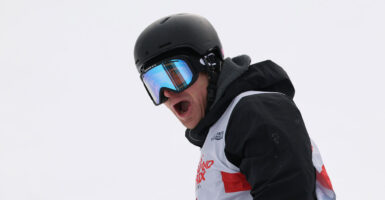 American skier Hunter Hess in helmet in goggles against a white background with his mouth open wide.