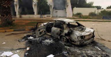 TOPSHOT - The wreckage of a burnt car is seen outside a building used by Ansar al-Sharia militia after it was torched by residents on November 25, 2013 in Benghazi. Military governor Colonel Abdullah al-Saidi declared a 