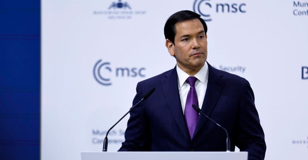 Marco Rubio looks off to his left as he speaks at a podium in front of white background with Munich Security Conference MSC logo.