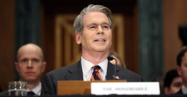 Scott Bessent smiles while testifying at a hearing.