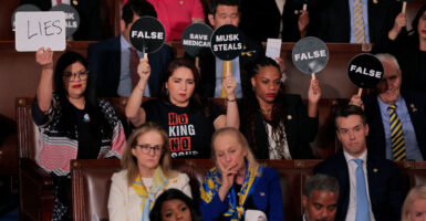 Democrat members of congress hold up signs and look on in anger during President Trump's 2025 address to Congress.
