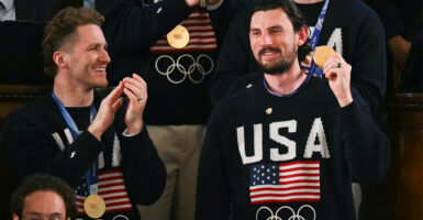 Goalie Connor Hellebuyck raises his gold medal as members of the US Men's Olympic hockey team are recogized by US President Donald Trump as he delivers the State of the Union address in the House Chamber of the US Capitol in Washington, DC, on February 24, 2026. (Photo by ANDREW CABALLERO-REYNOLDS / AFP via Getty Images)
