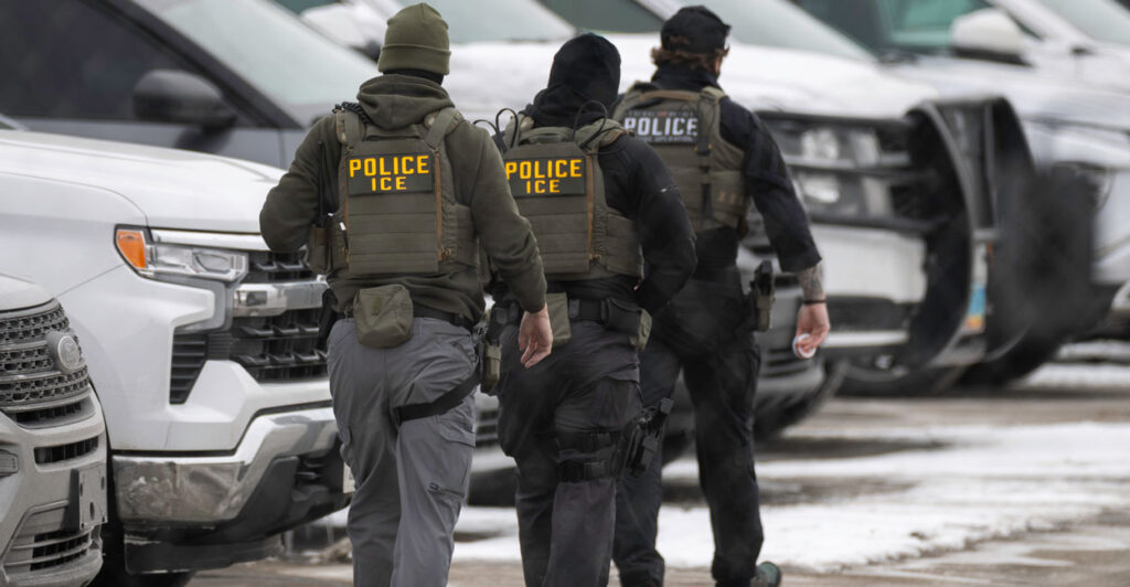 Three ICE officers are seen walking away in the snow.