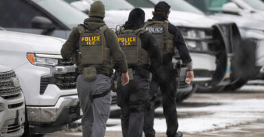 Three ICE officers are seen walking away in the snow.