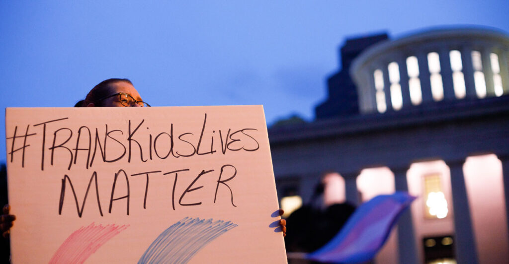 A person holds a sign reading "#TransKidsLivesMatter" outside the Ohio capitol.