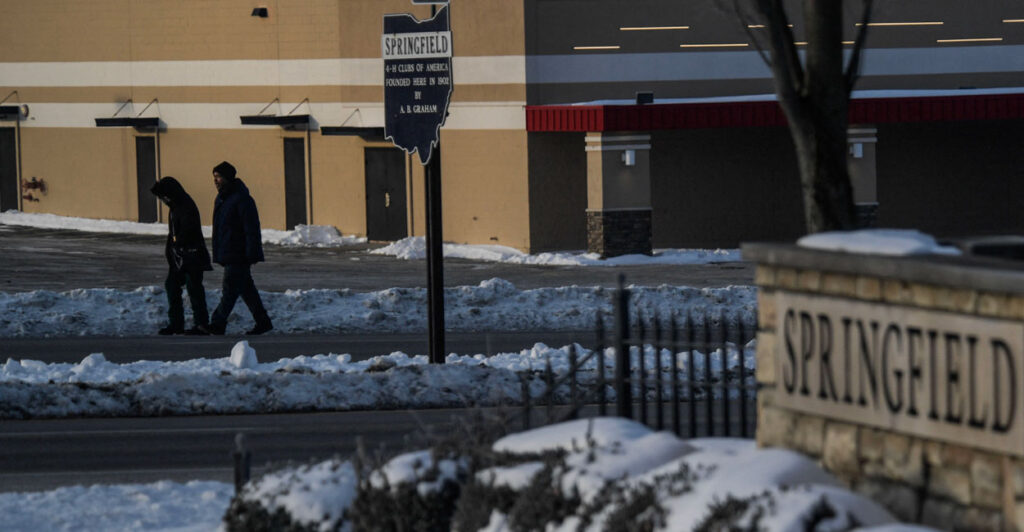 Residents walk by a sign for Springfield, Ohio in the snow.