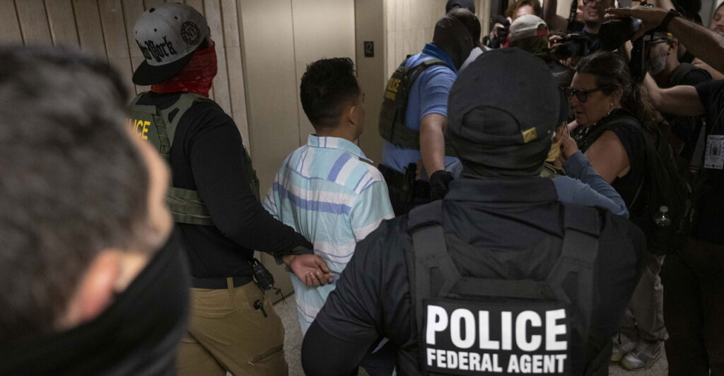 Federal agents lead a suspected illegal immigrant down a hallway.