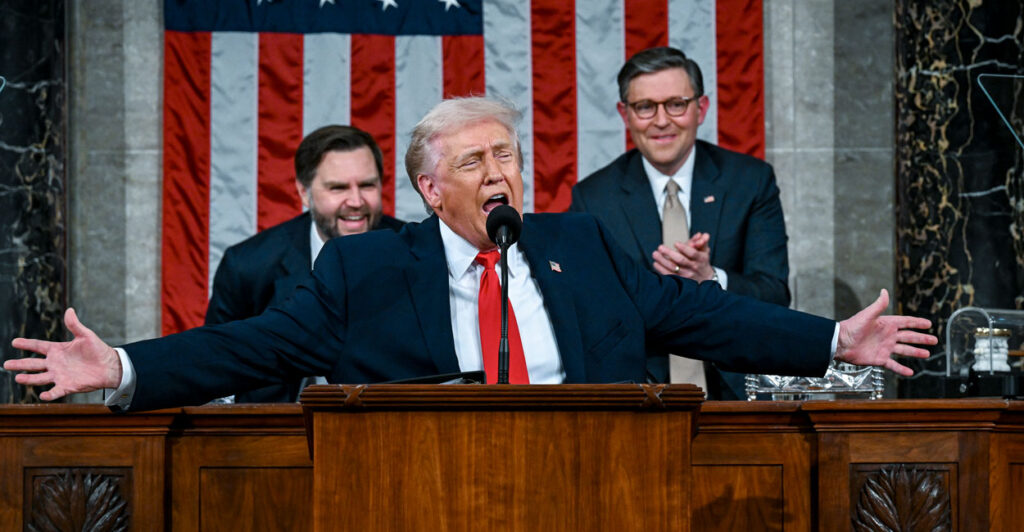 President Trump with his arms spread wide delivering his State of the Unioin, with JD Vance laughing and Mike Johnson clapping behind him.