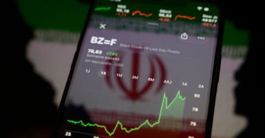 A smartphone showing graph indicating rise in crude oil prices against the background of an Iranian flag.
