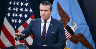 Pete Hegseth at podium with right hand extended palm down.