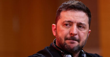 Close-up of Ukrainian President Volodymyr Zelenskyy with headphones around his neck.