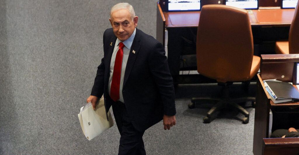 High angle shot of Benjamin Netanyahu walking through parliament with a folder.