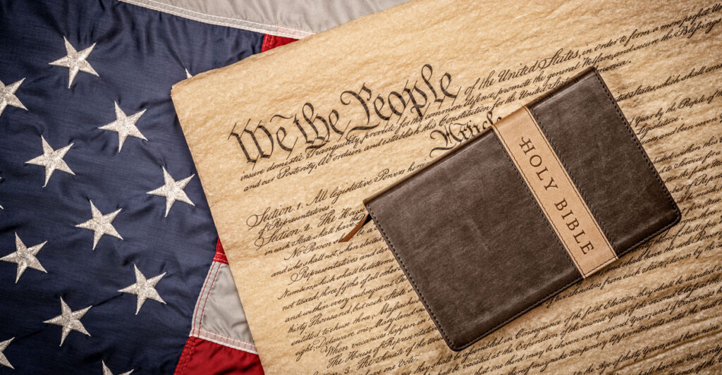 A Bible lays on a copy of the Constitution atop a flag.