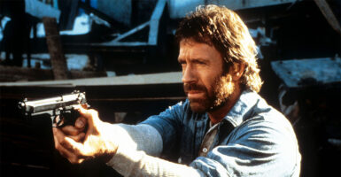 Chuck Norris points a gun in a scene from the film 'Hero And The Terror', 1988. (Cannon/Getty Images)