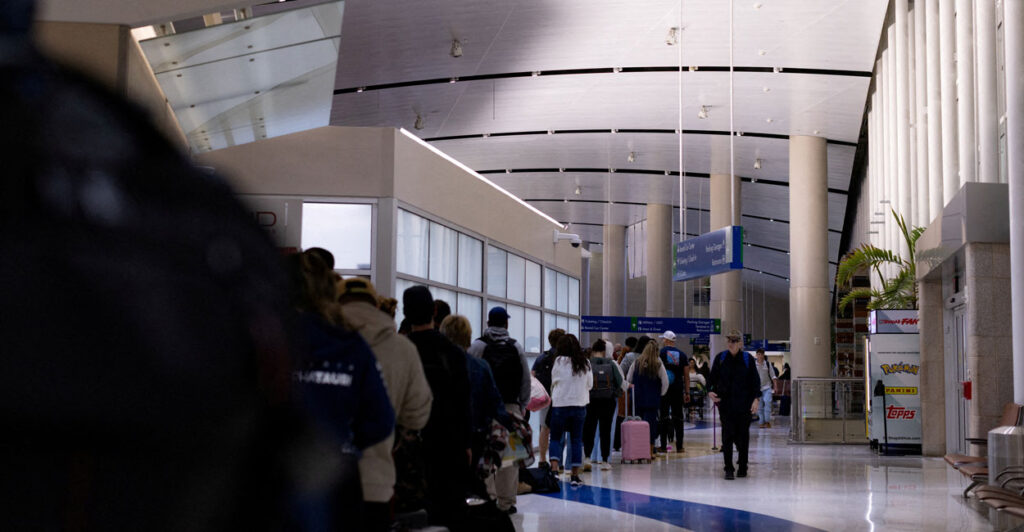Long line stretching in airport terminal to pass through security.