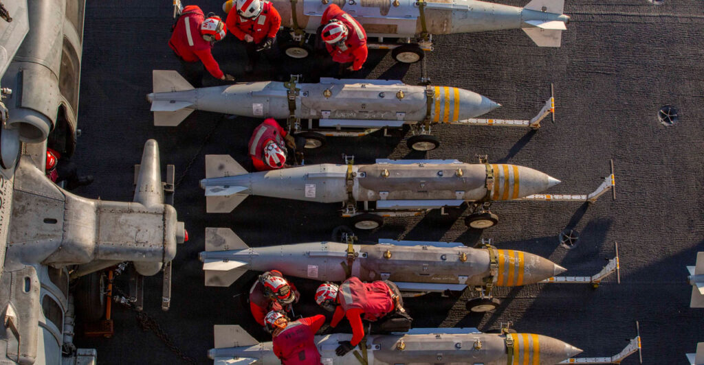 Overhead shot of U.S. Navy crew members inspecting a row of ordinance.
