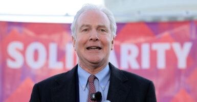 Sen. Chris Van Hollen, D-Md., speaks in front of a pink sign reading "Solidarity."