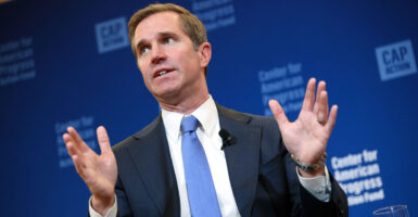 Gov. Andy Beshear speaks with his hands raised.