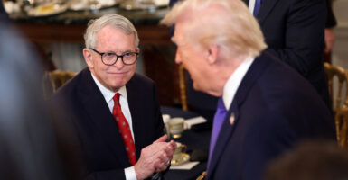 Gov. Mike DeWine smiles and applauds as President Donald Trump walks by.