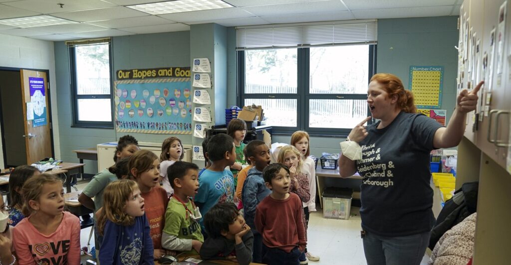 A female first grade teacher with students in a classroom.