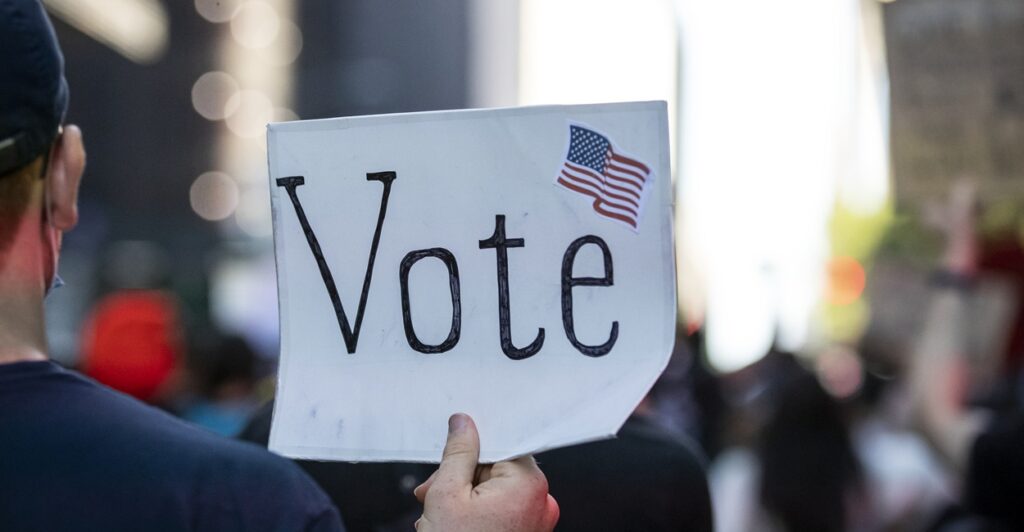 Man holding a sign that says "Vote."