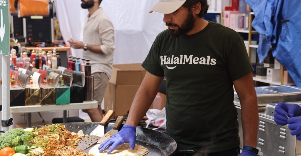 Man wearing shirt that says "halal meats" while cooking.