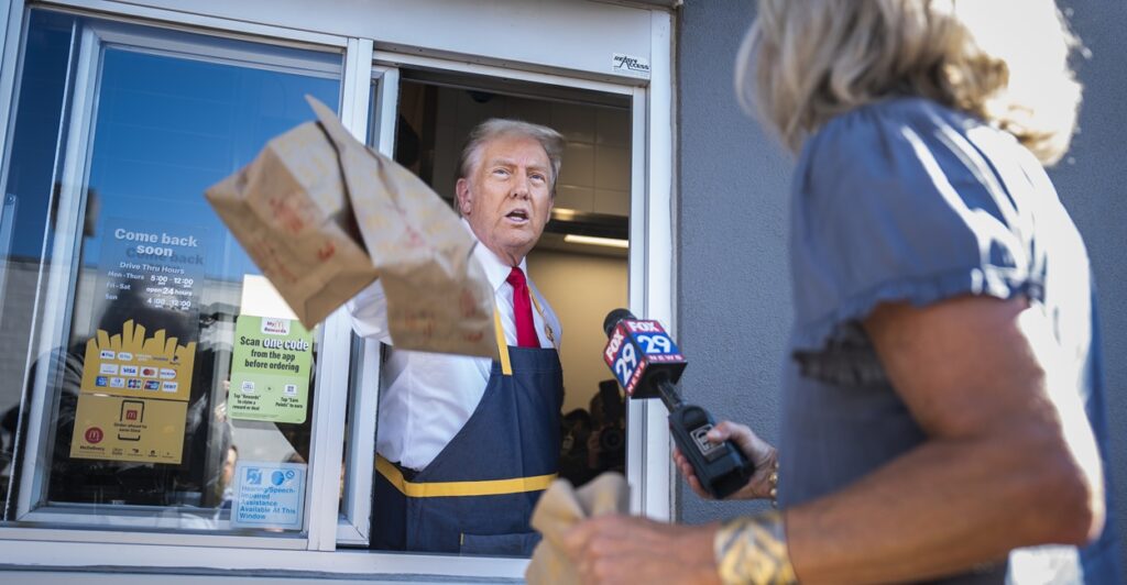 Donald Trump holding McDonalds bags out a window.