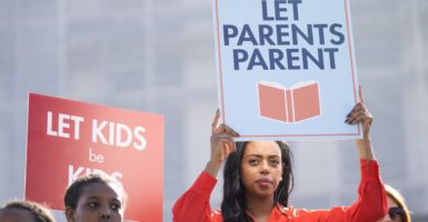 Woman holding sign that says "Let parents parent."