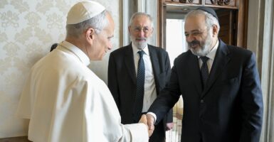 Pope Leo XIV shaking hands with Rabbi Raf Alfonso Arbib with another man standing behind