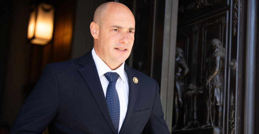 Rep. Greg Landsman buttons his suit jacket as he looks out from the Capitol.